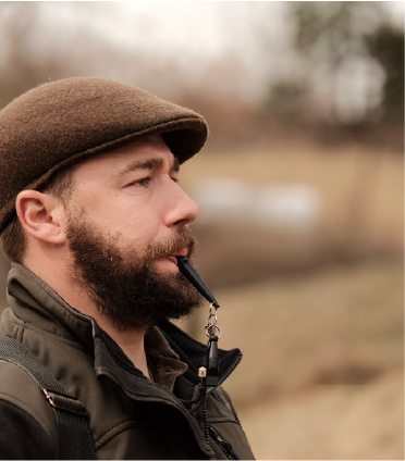 Jagdhund Trainer Andeas Goms mit grünem Hut und schwarzer Hundepfeife beim Dummytraining in Graz